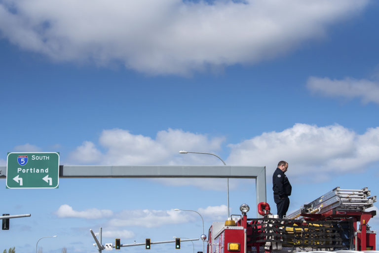 Jeff Peterson, a firefighter with Clark County Fire District 6, watches the funeral procession of Cowlitz County sheriff's Deputy Justin DeRosier as it passes under the 139th Street and Interstate 5 overpass on Wednesday morning, April 24, 2019.