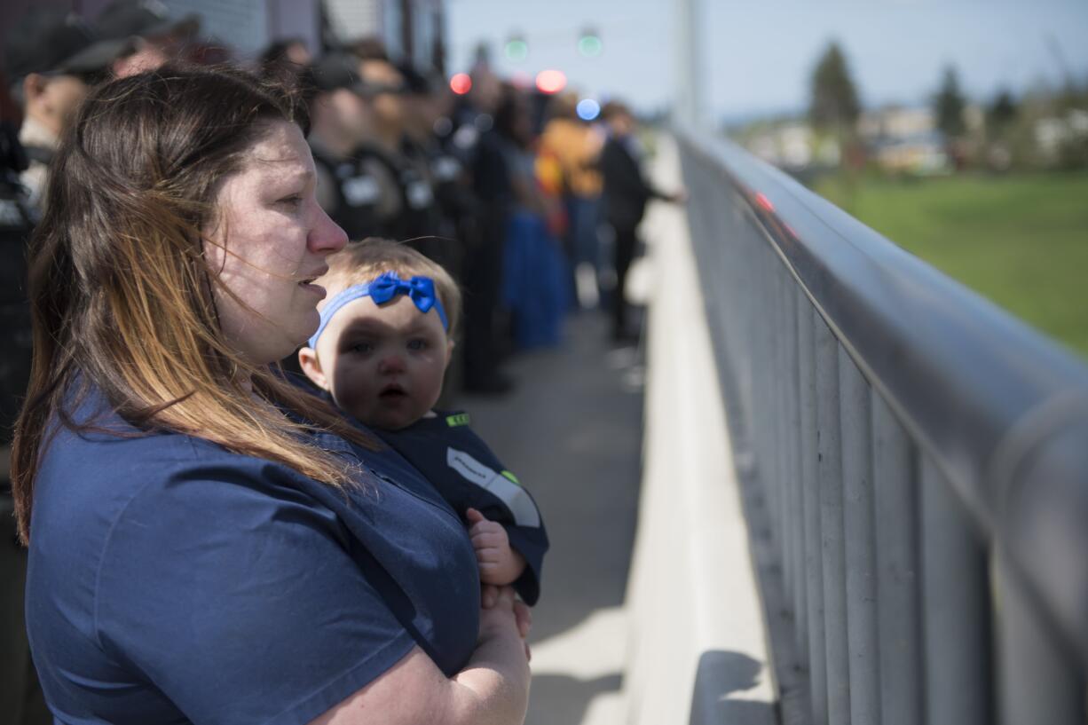 Rachael Weeks, and her 11-month-old daughter Remington Couch, watch the funeral procession for Cowlitz County sheriff's Deputy Justin DeRosier from the 139th Street and Interstate 5 overpass on Wednesday morning, April 24, 2019. Weeks said she previously worked with the wife of Deputy DeRosier at PeaceHealth Southwest Medical Center.