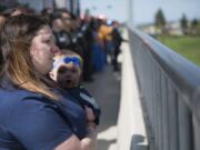 Rachael Weeks, and her 11-month-old daughter Remington Couch, watch the funeral procession for Cowlitz County sheriff's Deputy Justin DeRosier from the 139th Street and Interstate 5 overpass on Wednesday morning, April 24, 2019. Weeks said she previously worked with the wife of Deputy DeRosier at PeaceHealth Southwest Medical Center.