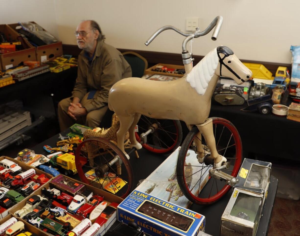 Terry Parker, 69, of Portland, sits near his vintage tricycle Sunday at the Vancouver Toy Junkies Vintage Toy Show and Sale. Below, a prop E.T., the Extra-Terrestrial, sits on display Sunday at the Vancouver Toy Junkies Vintage Toy Show and Sale.