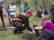 Volunteer Emma Brenneman helps a girl plant a tree at an Earth Day event at Salmon Creek Regional Park in 2017.