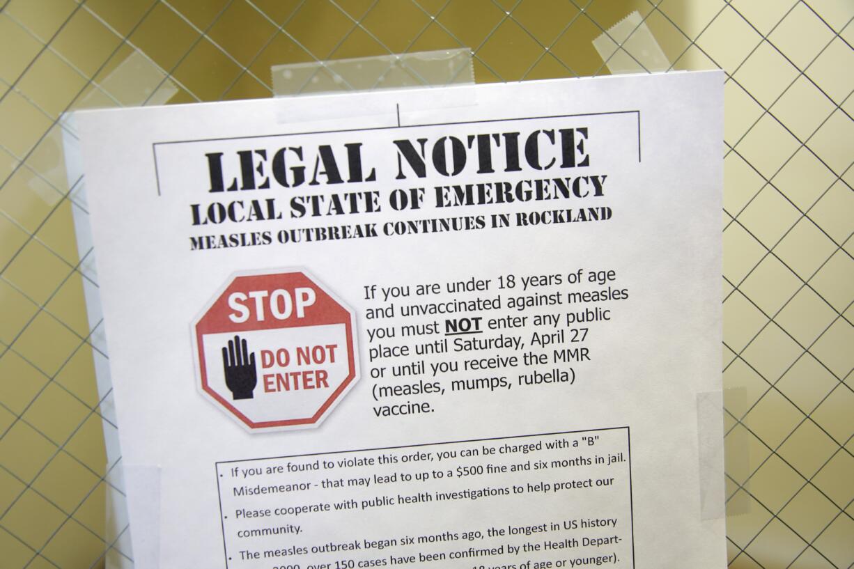 FILE - This Wednesday, March 27, 2019 file photo shows a sign explaining the local state of emergency because of a measles outbreak at the Rockland County Health Department in Pomona, N.Y. Measles is spread through the air when an infected person coughs or sneezes. It's so contagious that 90 percent of people who aren't immunized are infected if exposed to the virus, according to the Centers for Disease Control and Prevention.