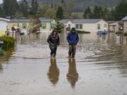 Shannon Archuleta, left, and her son Jett Archuleta wade through a flooded street in the Riverstone Mobile Home Park in Cottage Grove, Ore. Monday April, 8, 2019 to check on a family member after flood waters rose overnight.