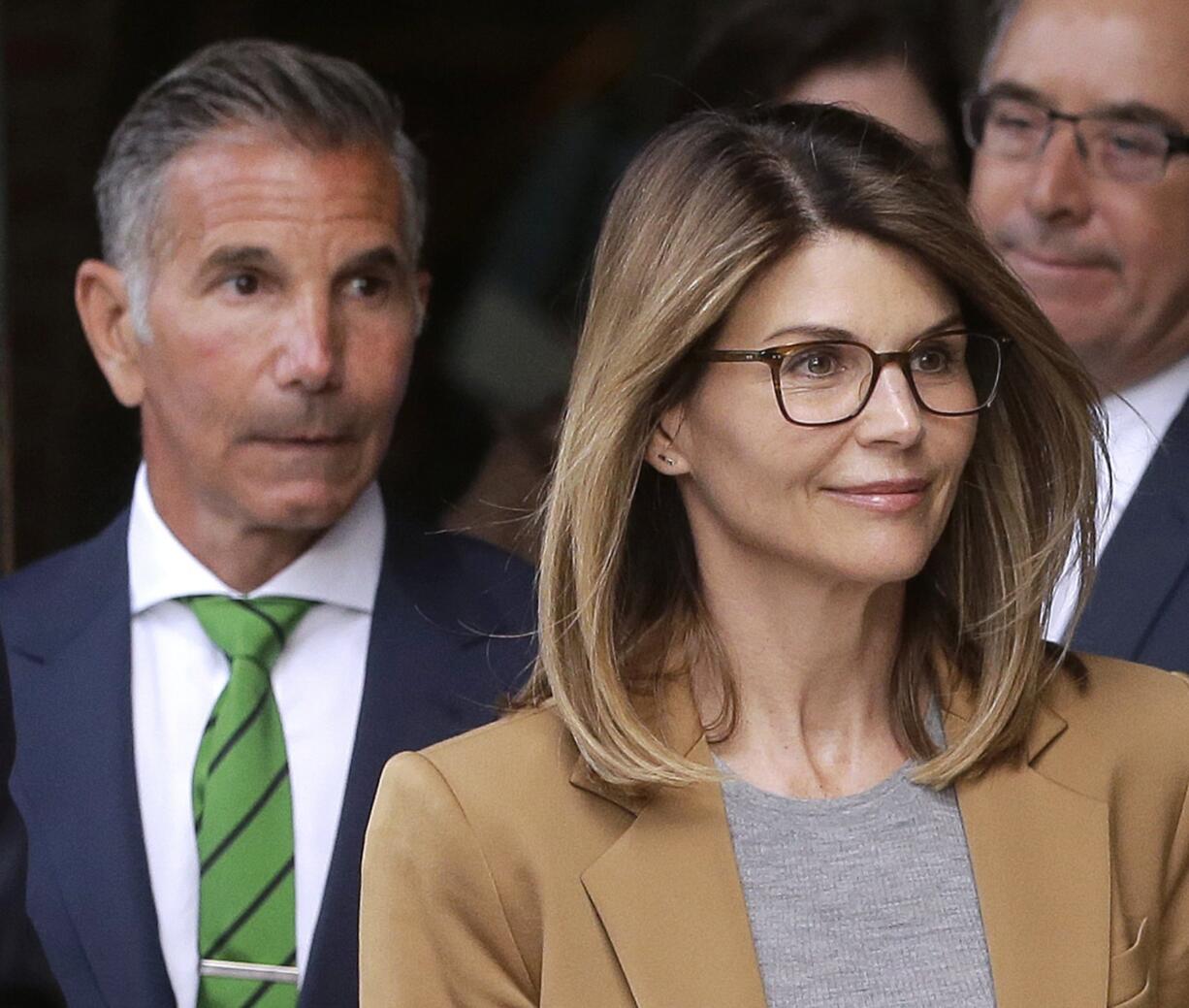 FILE - In this April 3, 2019 file photo, actress Lori Loughlin, front, and husband, clothing designer Mossimo Giannulli, left, depart federal court in Boston after facing charges in a nationwide college admissions bribery scandal. On Tuesday, April 9, Loughlin and Giannulli were among 16 prominent parents indicted on an additional charge of money laundering conspiracy in the case.