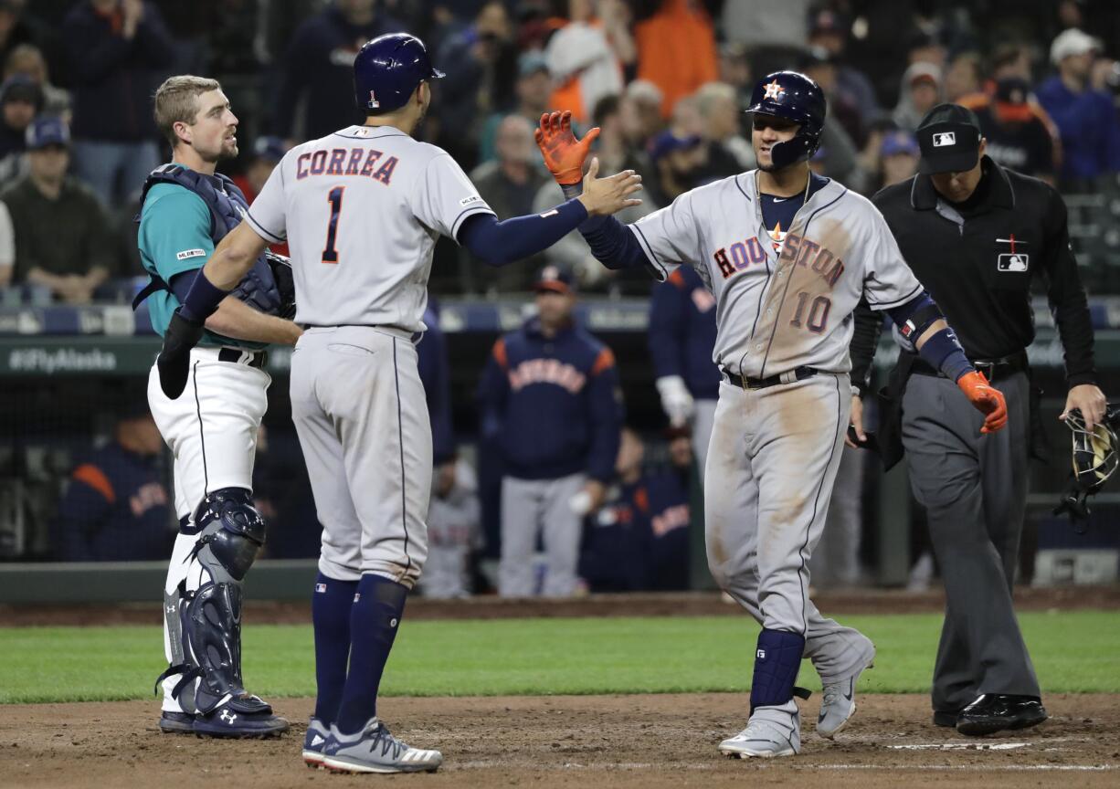 Houston Astros' Yuli Gurriel, right, is greeted at the plate by Carlos Correai (1) as Seattle Mariners catcher Tom Murphy, left, waits after Gurriel hit a grand slam during the eighth inning of a baseball game Friday, April 12, 2019, in Seattle. (AP Photo/Ted S.