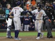 Houston Astros' Yuli Gurriel, right, is greeted at the plate by Carlos Correai (1) as Seattle Mariners catcher Tom Murphy, left, waits after Gurriel hit a grand slam during the eighth inning of a baseball game Friday, April 12, 2019, in Seattle. (AP Photo/Ted S.