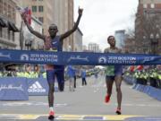 Lawrence Cherono, of Kenya, hits the tape to win the 123rd Boston Marathon in front of Lelisa Desisa, of Ethiopia, right, on Monday, April 15, 2019, in Boston.