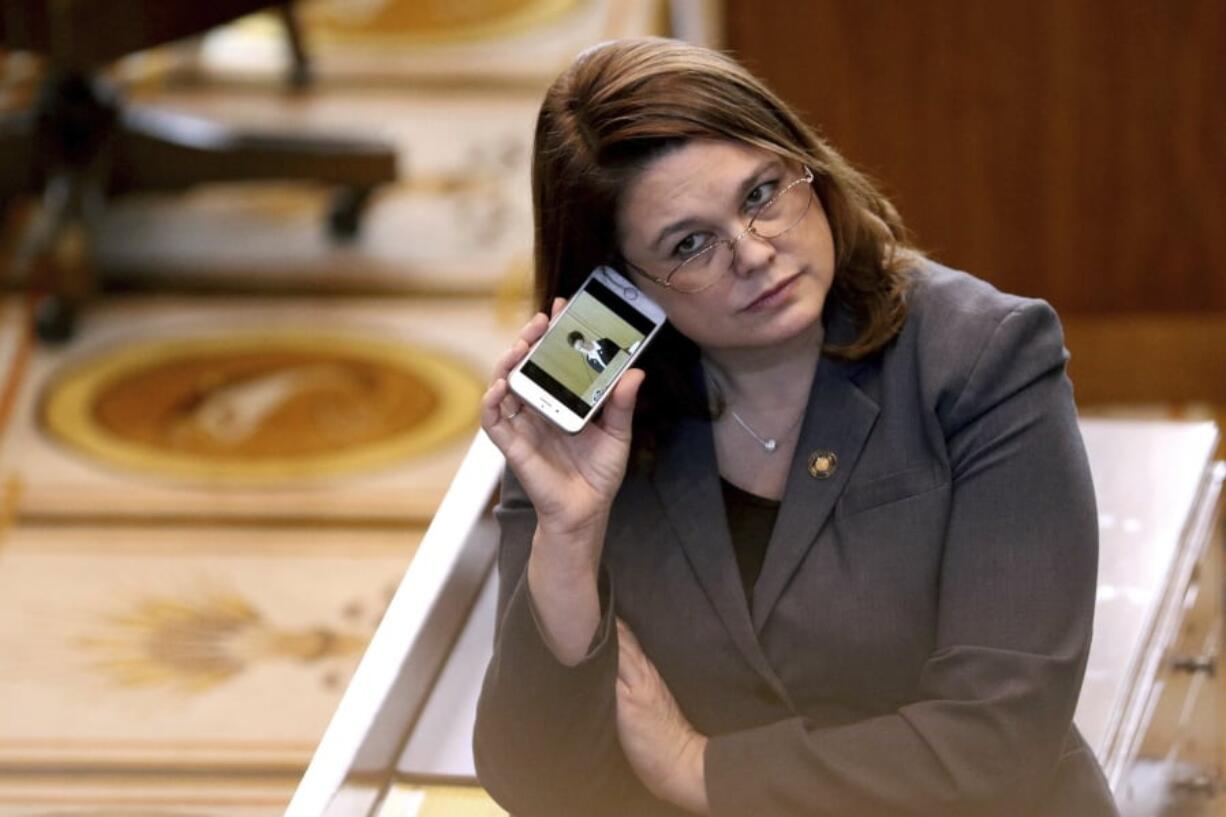 FILE - In this March 3, 2016, file photo, Oregon state Sen. Sara Gelser listens to a live stream as members of the House of Representatives finish business before adjourning the 2016 legislative session at the Oregon State Capitol in Salem, Ore. Oregon lawmakers including Gelser are demanding answers from the state’s child welfare agency after a report that a 9-year-old girl in foster care was sent to a Montana facility for six months and injected with Benadryl to control her behavior. A legislative hearing Thursday, April 11, 2019 largely focused on the news report this week by Oregon Public Broadcasting that also revealed caseworkers didn’t visit the girl for months.