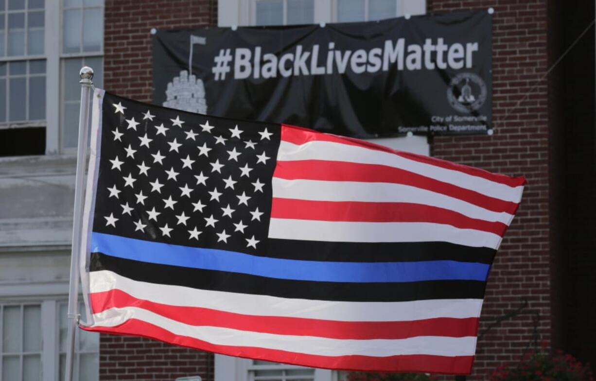 A flag with a blue and black stripes in support of law enforcement officers flies in 2016 at a protest by police and their supporters in Somerville, Mass.