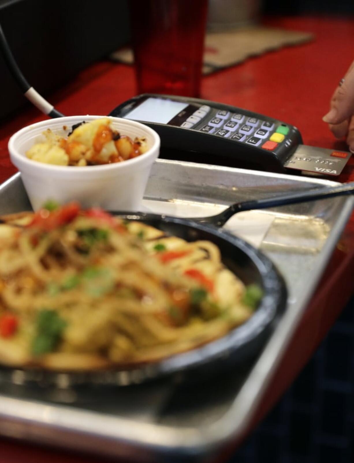 A customer uses a credit card machine to pay for food at Peli Peli Kitchen in Houston.