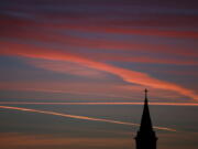 Contrails from jets glow pink as they are illuminated by the setting sun in the skies beyond a church in Kansas in 2014. According to a Gallup poll, the percentage of U.S. adults who belong to a church has fallen to a low of 50 percent last year.