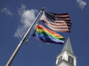 A gay pride rainbow flag flies along with the U.S. flag in front of the Asbury United Methodist Church in Prairie Village, Kan., on Friday.