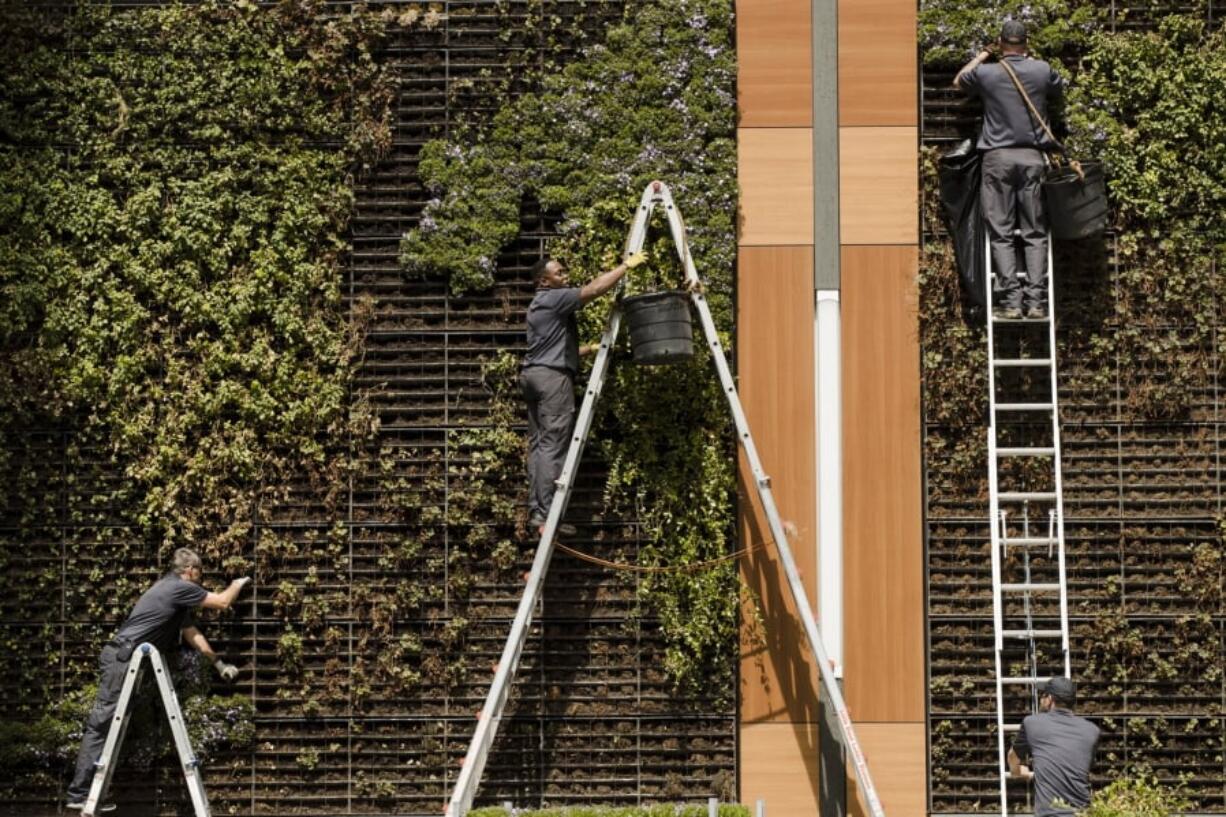 FILE - In this April 9, 2019, photo gardeners work on a vertical planters in Philadelphia. On Tuesday, April 30, the Labor Department releases the employment cost index for the first quarter, a measure of wage and benefit growth.