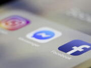 FILE- In this March 13, 2019, file photo Facebook, Messenger and Instagram apps are are displayed on an iPhone in New York. Facebook, Instagram and WhatsApp were temporarily down early Sunday, April 14. All three social media platforms, including Facebook Messenger, were affected by the outage.