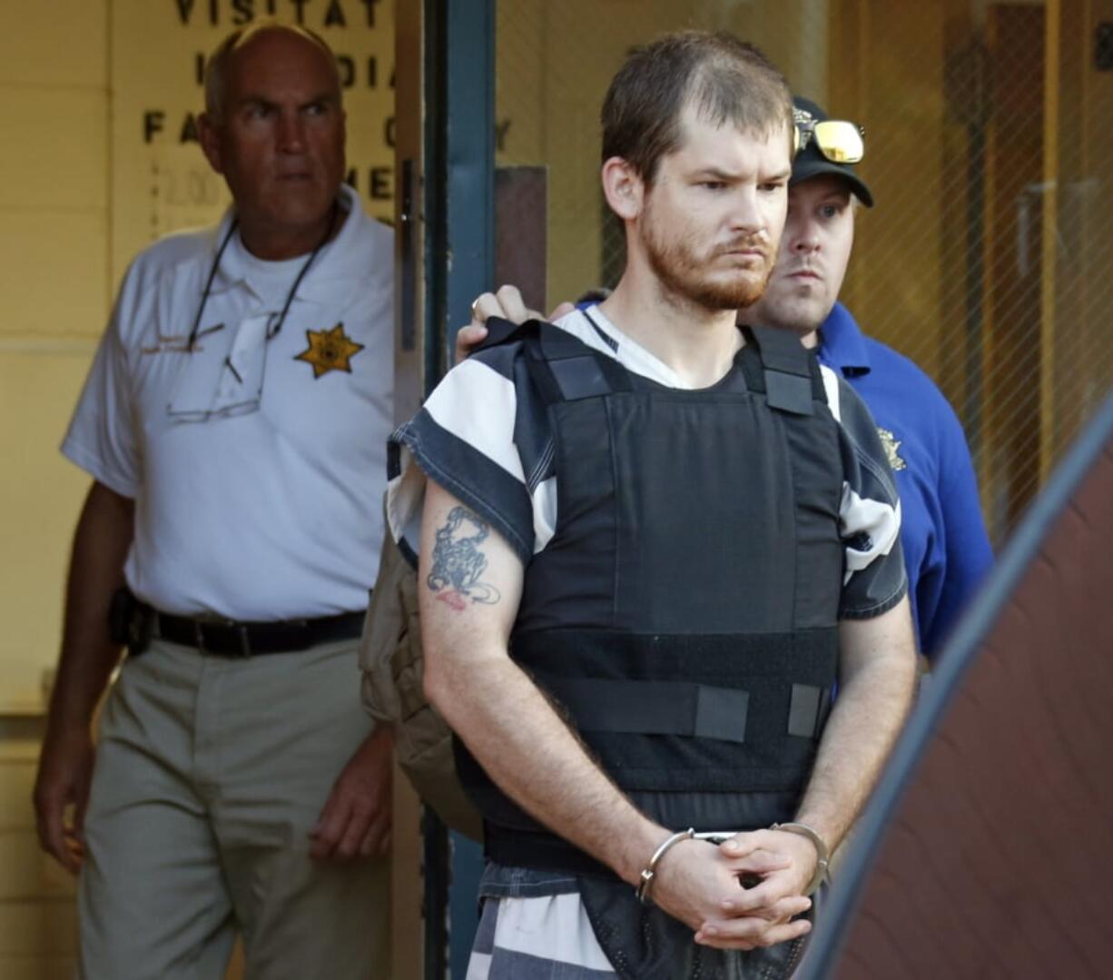 FILE - In this Thursday, Sept. 11, 2014 file photo,Smith County Sheriff Charlie Crumpton, left, watches as Timothy Ray Jones Jr., is escorted by lawmen out of the Smith County Jail to a vehicle for transport to Lexington County, S.C. in Raleigh, Miss. Jury selection is set to begin Monday, April 29, 2019 in the death penalty trial of Jones who police said killed his five young children in their South Carolina home. Authorities say after 37-year-old Timothy Jones Jr. killed his children, ages 8, 7, 6, 2 and 1, in their Lexington home in August 2014, he drove their bodies around for a week, burying them in Alabama and then being arrested in Mississippi. Court records show defense attorneys plan an insanity defense for Jones. (AP Photo/Rogelio V.