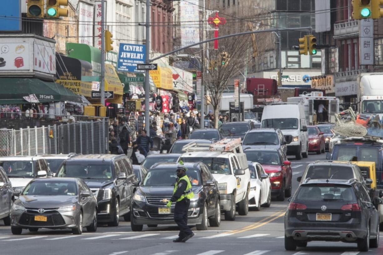 In this May 28, 2019 photo, a police officer directs rush hour traffic on Canal Street in New York. Long ringed by some of the most expensive toll roads in the U.S., New York City is poised to take things even further with a plan to use automated license plate readers to charge drivers who motor into the most congested parts of Manhattan during times when crosstown traffic is at its worst.