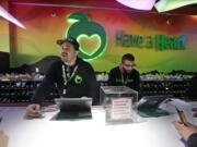 Employees Dan Giroux, left, and Dustin Barrington ring up sales for customers at a marijuana shop in Seattle. When Washington and Colorado launched their pioneering marijuana industries in the face of U.S. government prohibition, they imposed strict rules in hopes of keeping the U.S. Justice Department at bay. Five years later, federal authorities have stayed away, but the industry says it has been stifled by over-regulation. Lawmakers in both states have heard the complaints and are moving to ease the rules.