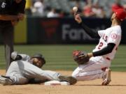 Los Angeles Angels shortstop Andrelton Simmons, right, tosses the ball after Seattle Mariners' Domingo Santana was tagged out trying to stretch a single into a double during the sixth inning of a baseball game in Anaheim, Calif., Sunday, April 21, 2019.