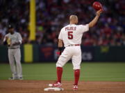 Los Angeles Angels’ Albert Pujols, right, tips his helmet to fans after hitting an RBI double as Seattle Mariners shortstop Tim Beckham claps during the third inning of a baseball game Saturday, April 20, 2019, in Anaheim, Calif. With that RBI, Pujols tied Babe Ruth for 5th place on the all-time RBI list with 1,992. (AP Photo/Mark J.