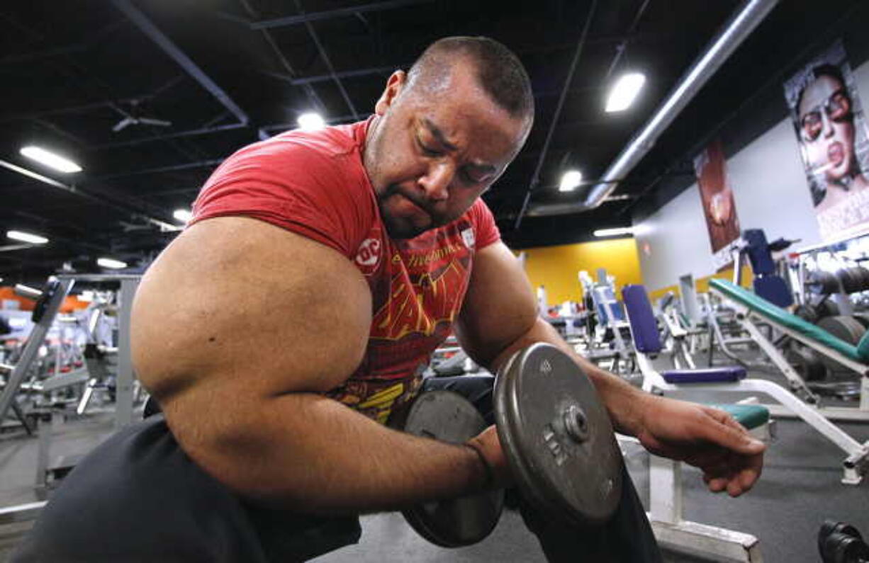 In this Nov. 16, 2012, file photo, Egyptian body builder Moustafa Ismail lifts free weights during his daily workout in Milford, Mass. On Monday, April 22, 2019, Merriam-Webster added the definition of swole to it's online dictionary, with the meaning "extremely muscular: having a physique enhanced by bodybuilding exercises." Ismail once was given the title of world's biggest arms, biceps and triceps, by the Guinness Book of World Records.