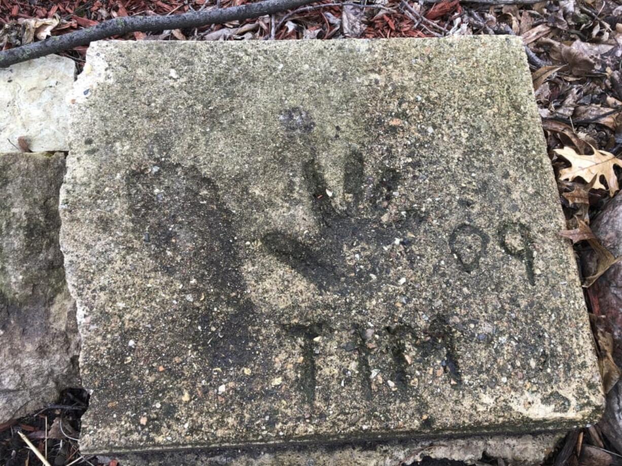 A slab of concrete sits in the backyard of the house where Timmothy Pitzen used to live in Aurora, Ill., Thursday, April, 4, 2019. The man who lives in the house now, Pedro Melendez, says he didn’t know the boy but saved the concrete slab with Tim’s name, handprint and footprint etched in it when he redid the back patio. Authorities conducted DNA testing to try to determine Thursday whether a teenager found wandering the streets of a Kentucky town is who he claims to be — an Illinois boy who disappeared eight years ago around the time his mother took her own life.