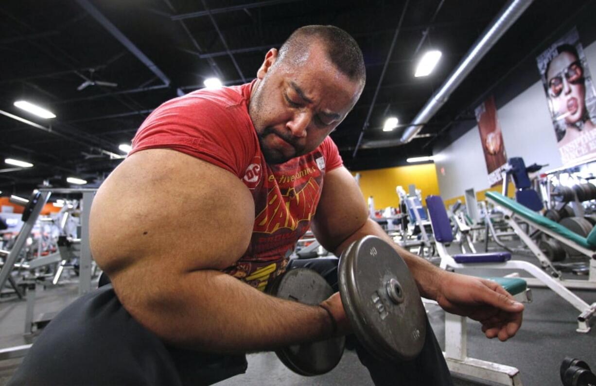 In this Nov. 16, 2012, file photo, Egyptian body builder Moustafa Ismail lifts free weights during his daily workout in Milford, Mass. On Monday, April 22, 2019, Merriam-Webster added the definition of swole to it’s online dictionary, with the meaning “extremely muscular: having a physique enhanced by bodybuilding exercises.” Ismail once was given the title of world’s biggest arms, biceps and triceps, by the Guinness Book of World Records.