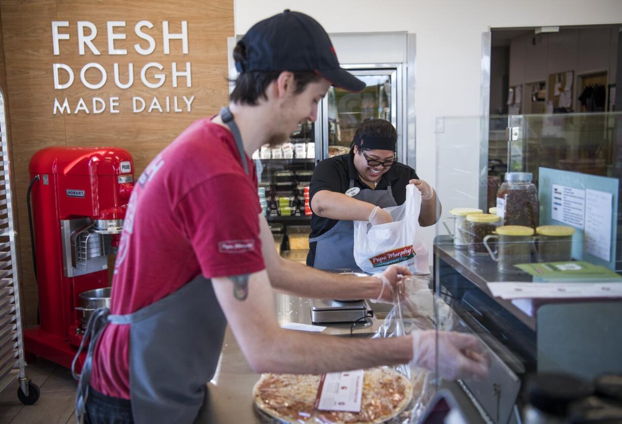 Papa Murphy's employee Chris Ritch, left, and manager Gladys Marron, right, prepare an order at the store on Southeast Mill Plain Boulevard in Vancouver.