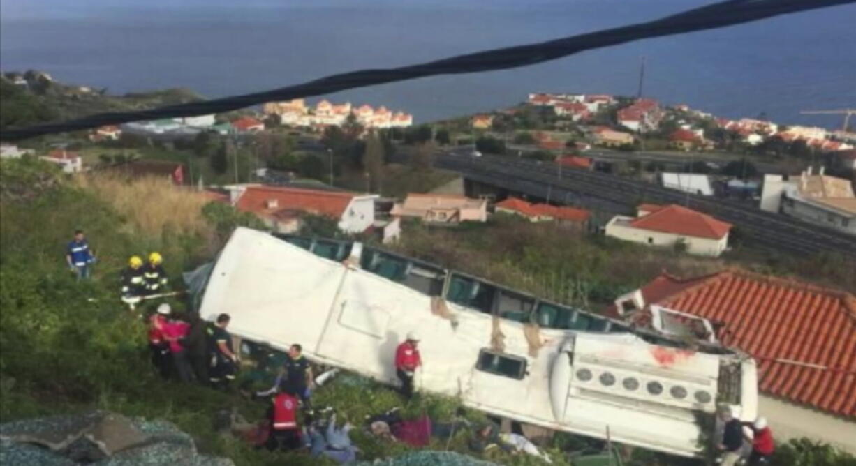 In this image from video, emergency services attend the scene after a tour bus crashed at Canico, on Portugal’s Madeira Island, Wednesday April 17, 2019. Some 28 people are reported to have died in the crash, most of them German tourists, local mayor Filipe Sousa told TV news.