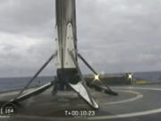 This Thursday, April 11, 2091 image from video made available by SpaceX shows a Falcon rocket booster shortly after landing on a barge in the Atlantic Ocean off Florida. On Tuesday, April 16, the company confirmed that the unsecured core booster toppled onto the platform over the weekend, as waves reached 8 to 10 feet. SpaceX chief Elon Musk says custom devices to secure the booster weren’t ready in time for this second flight of the Falcon Heavy.