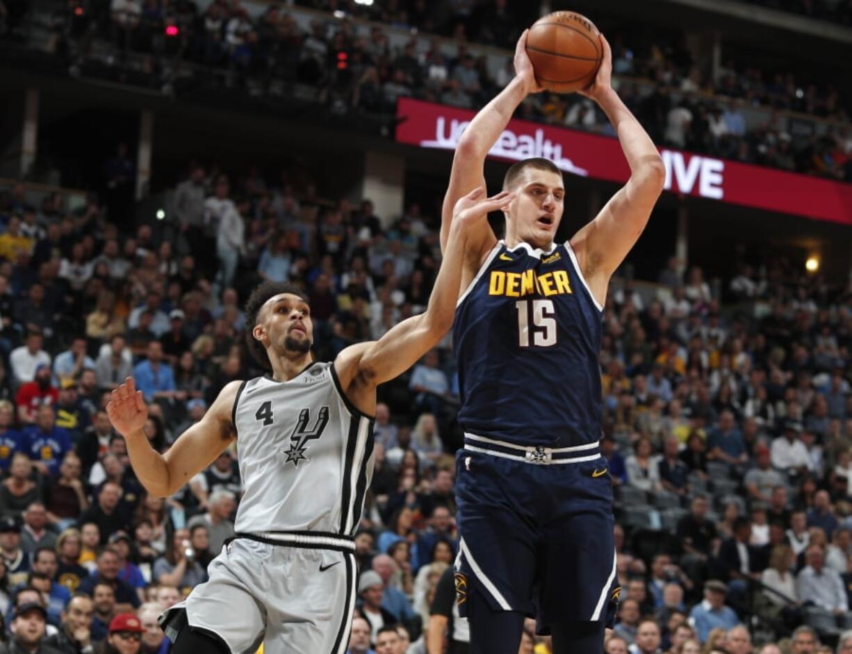 Denver Nuggets center Nikola Jokic, right, pulls in a rebound as San Antonio Spurs guard Derrick White defends in the first half of Game 7 of an NBA basketball first-round playoff series Saturday, April 27, 2019, in Denver.