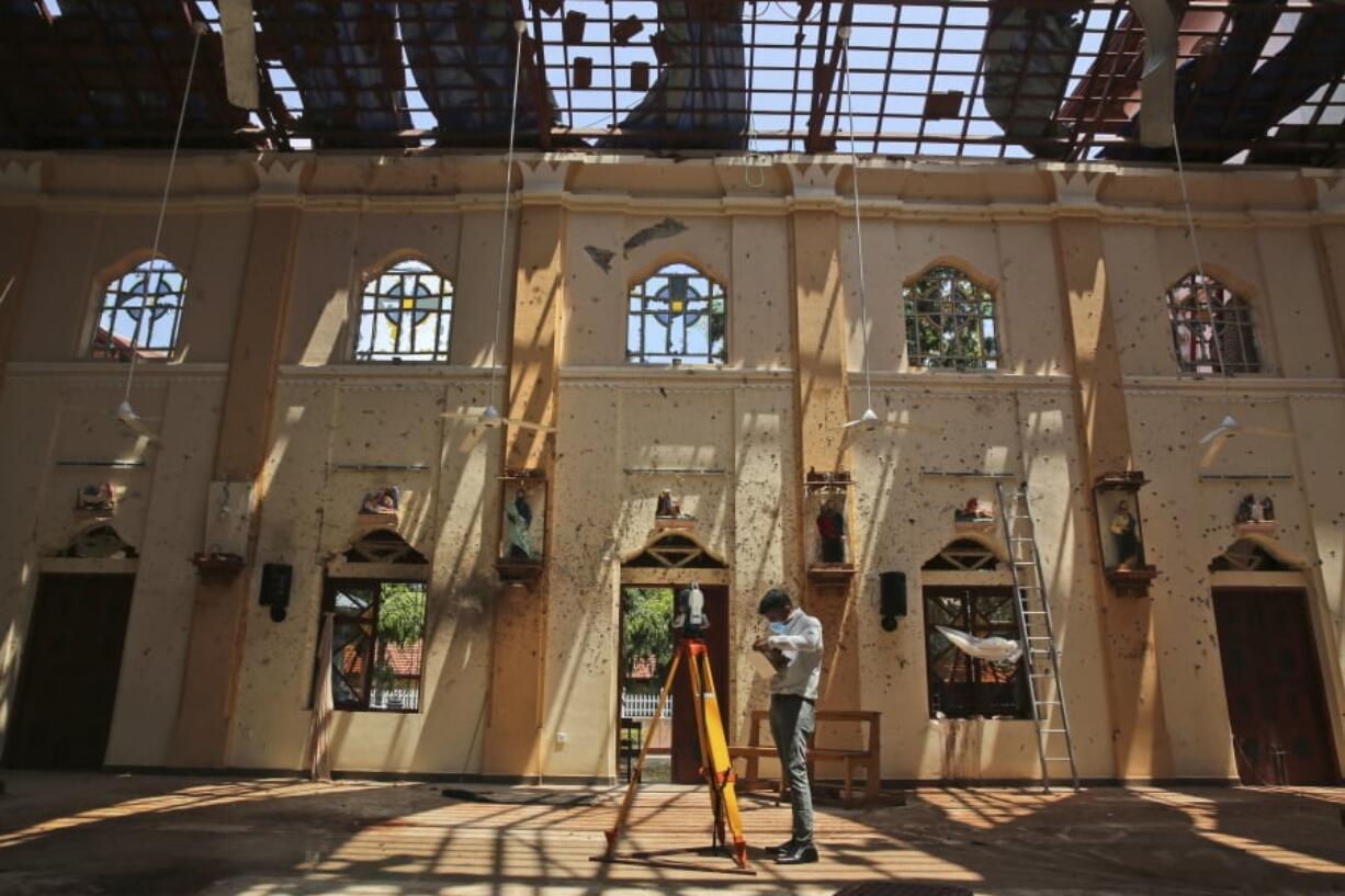 In this Thursday, April 25, 2019 photo, sunlight steams in from gaping holes, as a surveyor works at St. Sebastian’s Church, where a suicide bomber blew himself up on Easter Sunday in Negombo, north of Colombo, Sri Lanka. Nearly a week later, the smell of death is everywhere, though the bodies are long gone. Yet somehow, there’s a beauty to St. Sebastian’s, a neighborhood church in a Catholic enclave north of Sri Lanka’s capital. You can see the beauty in the broken stained-glass windows. It’s there in the little statues that refused to fall over, and despite the swarms of police and soldiers who seem to be everywhere now in the streets of the seaside town of Negombo.