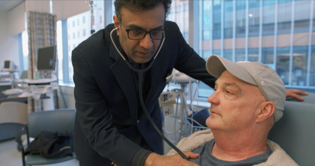 Dr. Mandeep Mehra, executive director of Brigham’s Center for Advanced Heart Disease, checks on patient James Sullivon at the hospital in Boston. Sullivon, who received a hepatitis C-positive heart transplant, was given antiviral medicine shortly after the procedure in hopes of blocking hepatitis C infection rather than having to treat it.