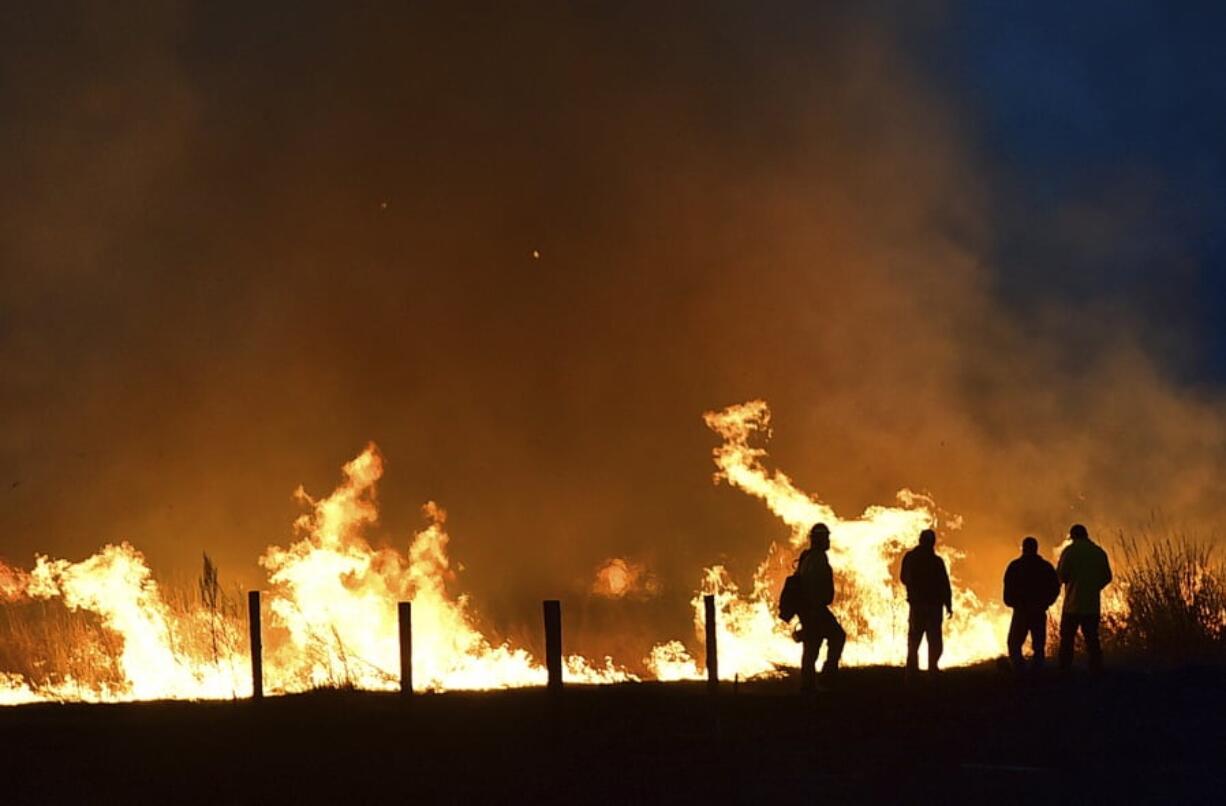 Lame Deer, Mont., residents watch Sunday as a fire races across a field on the edge of town. The blaze forced the evacuations of about 2,000 people.