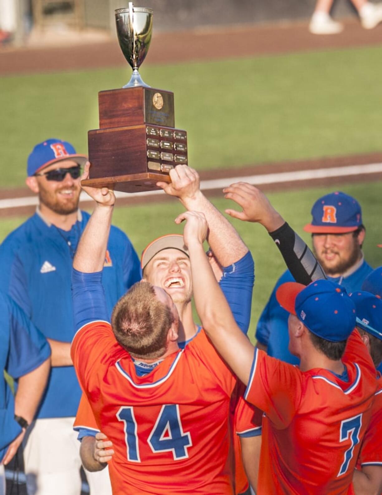 Ridgefield’s Brock Harrison, 14, holds up a 2A district championship trophy as Spencer Andersen, facing, and Kellen Bringhurst, 7, reach for it Friday at Propstra Stadium. Ridgefield topped Columbia River 4-2 to win their first district title since 2006.