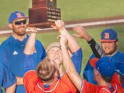 Ridgefield’s Brock Harrison, 14, holds up a 2A district championship trophy as Spencer Andersen, facing, and Kellen Bringhurst, 7, reach for it Friday at Propstra Stadium. Ridgefield topped Columbia River 4-2 to win their first district title since 2006.