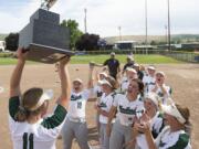 Woodland's Olivia Grey holds up the state championship trophy as her teammates celebrate after a 3-0 victory over W.F. West on Saturday, May 25, 2019 at Carlon Park in Selah, Wash.