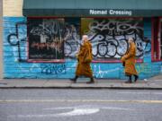 Ajahn Sudanto, left, and Ajahn Kassapo do their alms round to accept food offerings along Hawthorne Boulevard in Portland. “When we go into Portland once a month, maybe nine months of the year, it tends to be a lot more serendipitous what will happen,” Ajahn Sudanto said.