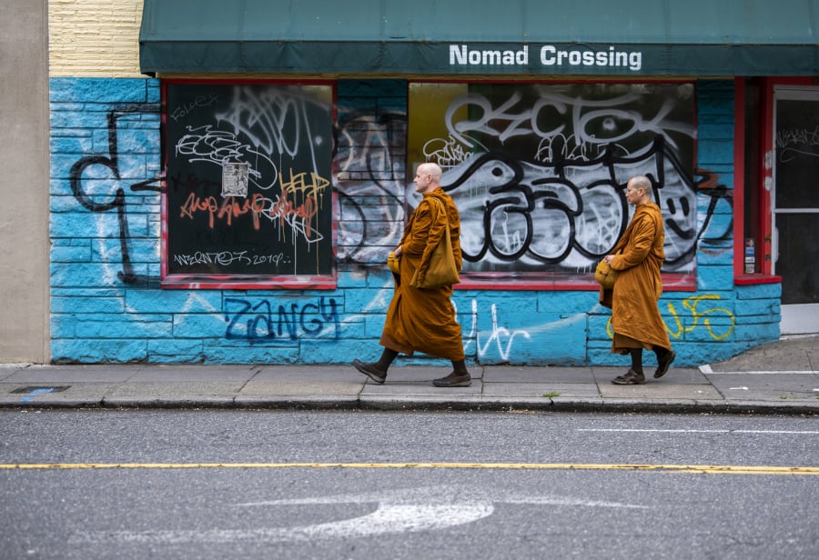 Ajahn Sudanto, left, and Ajahn Kassapo do their alms round to accept food offerings along Hawthorne Boulevard in Portland. “When we go into Portland once a month, maybe nine months of the year, it tends to be a lot more serendipitous what will happen,” Ajahn Sudanto said.