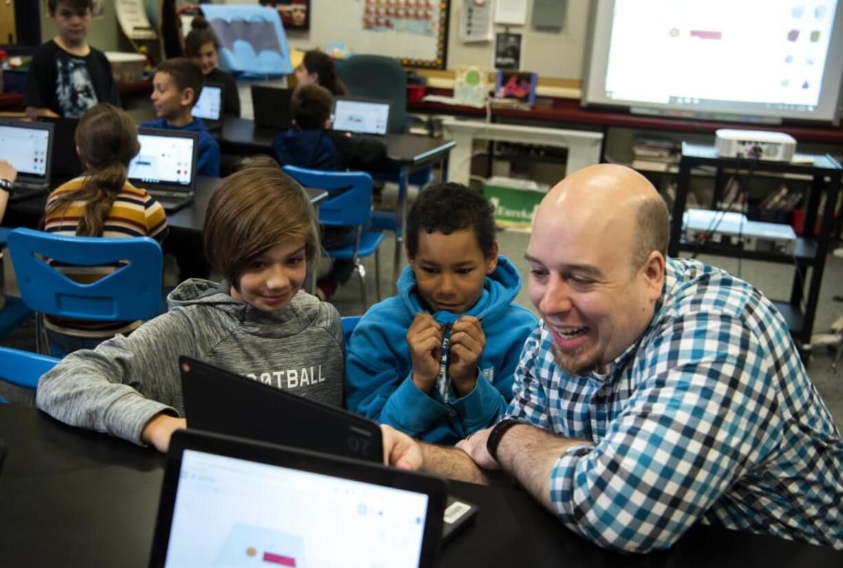 Burnt Bridge Creek Elementary fifth-graders Uriah Carlston, left, and Jonathan Suhajda work with volunteer Luke Loeffler on a CAD 3D-modeling program during the makerspace program at the school in Vancouver. The program brings in volunteers with different high-tech skills to share their knowledge with the students.