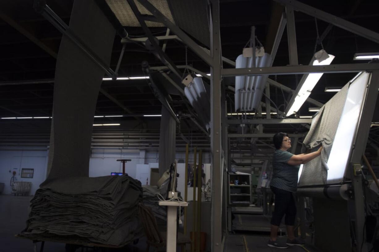 Nadia Niaitin checks the quality of a roll of woven wool at Pendleton’s Washougal mill.