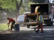 Matt Buttrell of Arborscape Tree Care, left, joins colleague Eulices Ibarra as they help prepare for future road preservation work on April 25 in Vancouver’s Rose Village neighborhood.