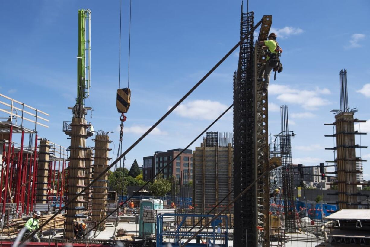 A construction worker scales the side of a structure while working on the Hotel Indigo and Kirkland Tower project at The Waterfront Vancouver.