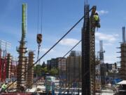 A construction worker scales the side of a structure while working on the Hotel Indigo and Kirkland Tower project at The Waterfront Vancouver.