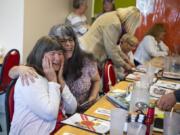 Kathy Janssen White, left, and Debbie Lowry laugh and embrace at Nayhely’s Place while perusing photos and remembering tales of growing up in the “V Street Gang.” That’s an enduring, multigenerational neighborhood group that started coming together in 1958 around the corner of V and 39th streets in Vancouver. A remarkable 61 years later, their reunions and friendships continue.