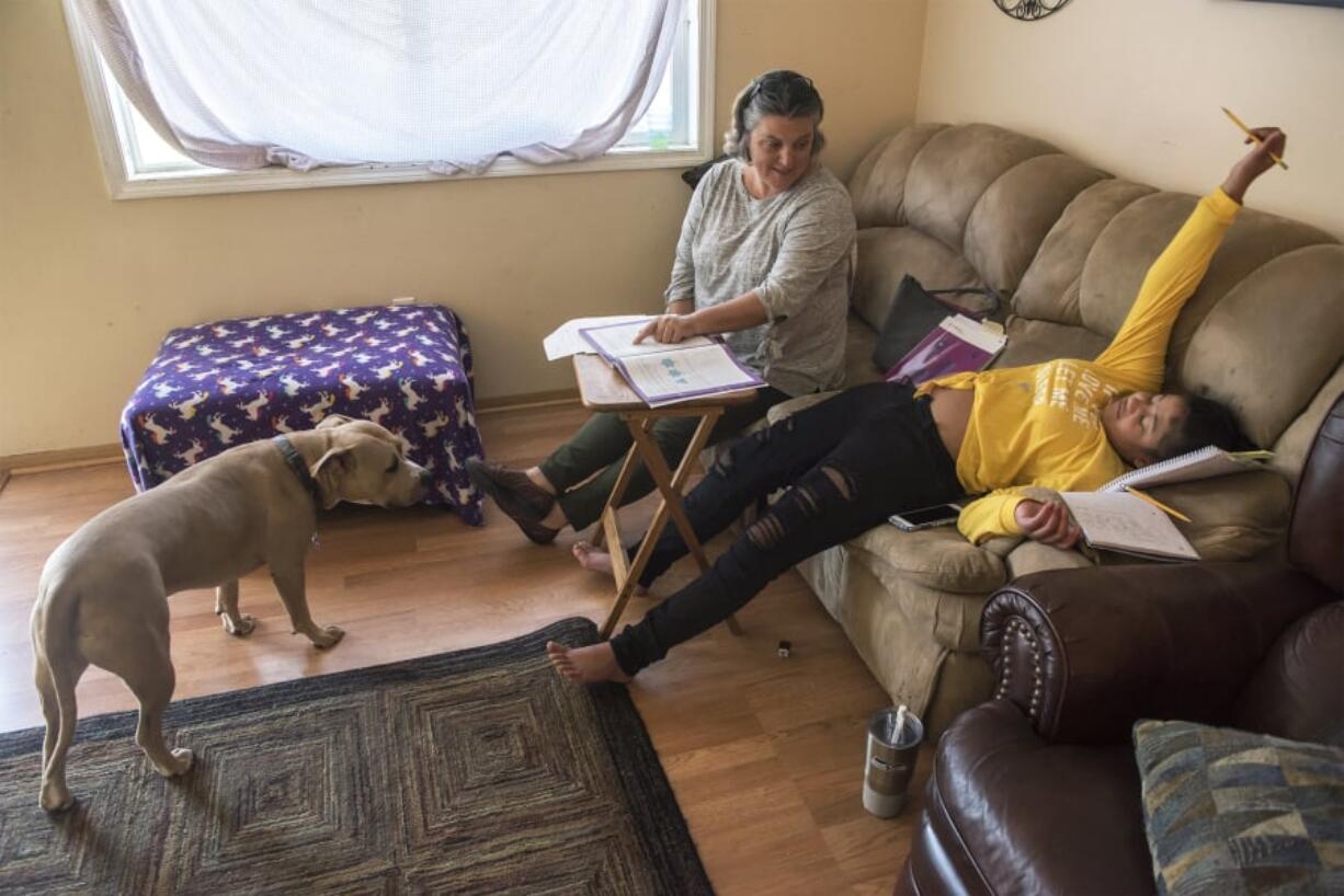 Jessica Lowery, a paraeducator with the Washougal School District, left, laughs as DejaRay Smith reacts to not knowing the answer to a math problem during a home school session at her Washougal home. DejaRay spent 79 days in the hospital because of a MRSA infection. She returned to school this week.