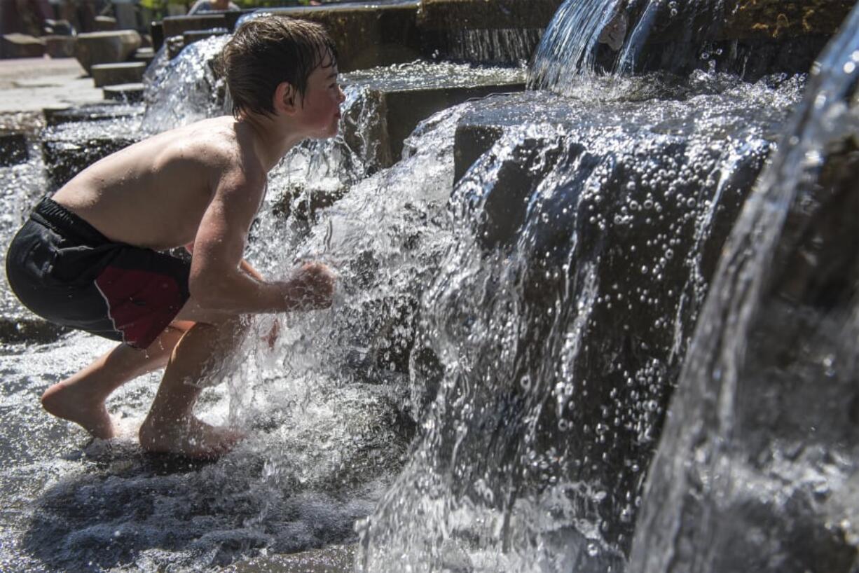 Kayden Kuehl, 7, of Vancouver prepares to dip his head under the water in Esther Short Park on Wednesday afternoon. The water feature, in the park’s southeast corner, is popular with hot kids on warm days.