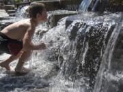 Kayden Kuehl, 7, of Vancouver prepares to dip his head under the water in Esther Short Park on Wednesday afternoon. The water feature, in the park’s southeast corner, is popular with hot kids on warm days.