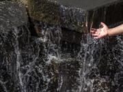 Vanessa Vizcaino, 4, of Vancouver reaches out to touch the flowing water inside the water feature at Esther Short Park on earlier this month.