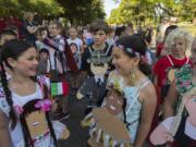 Lake Shore Elementary School third-graders Heaven Rodriguez, with braids, who was representing Mexico, joins classmate Isabella Lester, both 9, who was representing Native Americans, as they wait for the annual Children's Cultural Parade to begin at Fort Vancouver National Historic Site on Friday morning, May 10, 2019. Over 1,500 third grade students celebrated learning, community and diversity as they marched through the parade route and ended at the stockade with a speech by Gov. Jay Inslee.