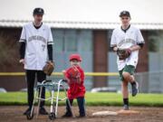 Jesuit High School sophomores Ben Eilers, left, and Cole Odegard, right, stand at second base with Austin Justin, 6, as they wait for the batter to swing during his first Miracle League baseball game at Union High School in April. The Vancouver Miracle League gives children with disabilities an opportunity to play baseball.